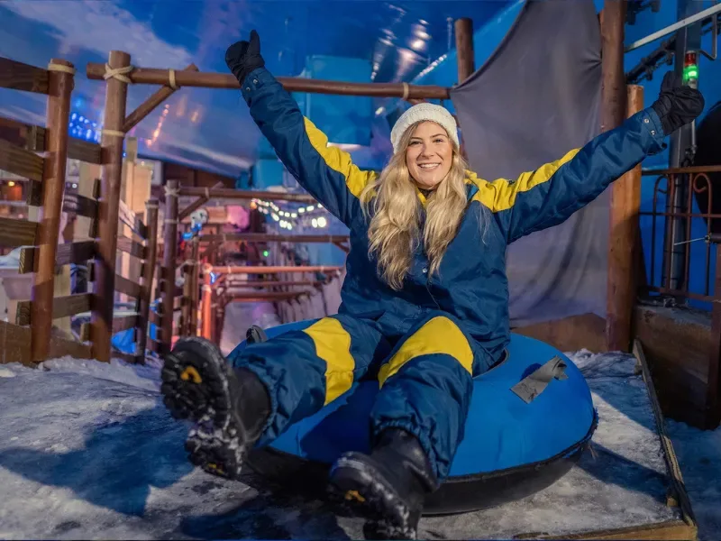 mulher comemorando que vai participar de uma atração de escorregador no gelo do snowland