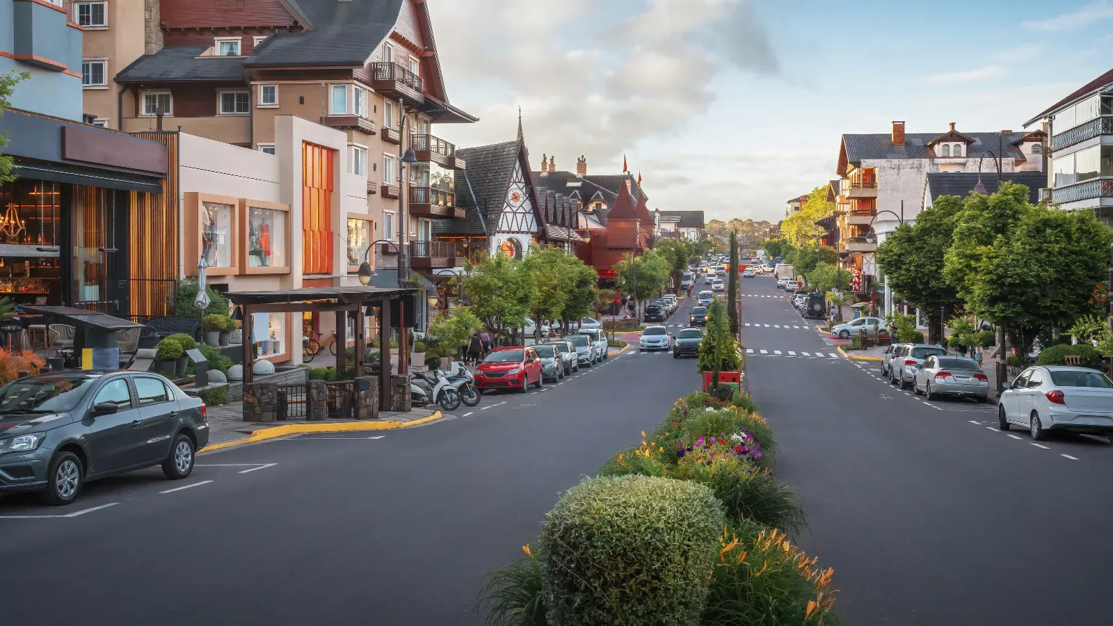 Avenida Bordes de Medeiros em Gramado, a rua esta bem vazia com poucos carros trafegando, um ddia ensolarado de verão com jardins bem verdes